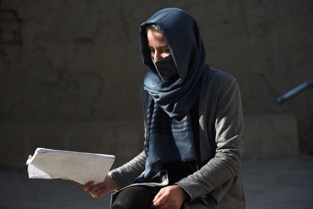 An unhappy Afghan scholar carrying a manuscript 