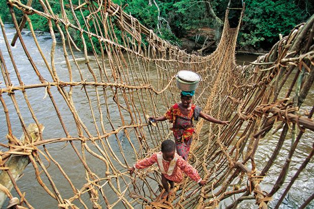 African woman and child crossing rope bridge