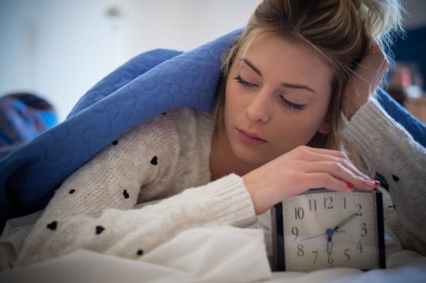 A young woman turns off an alarm clock
