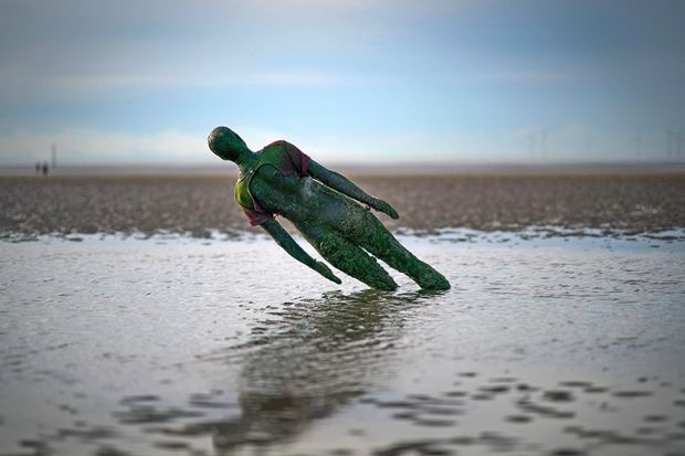 A statue in Antony Gormley’s art installation ‘Another Place’ at Crosby Beach subsides in the sand in Liverpool, England. To illustrate that without adequate funding for university teaching, the UK government is undermining the creative industries.