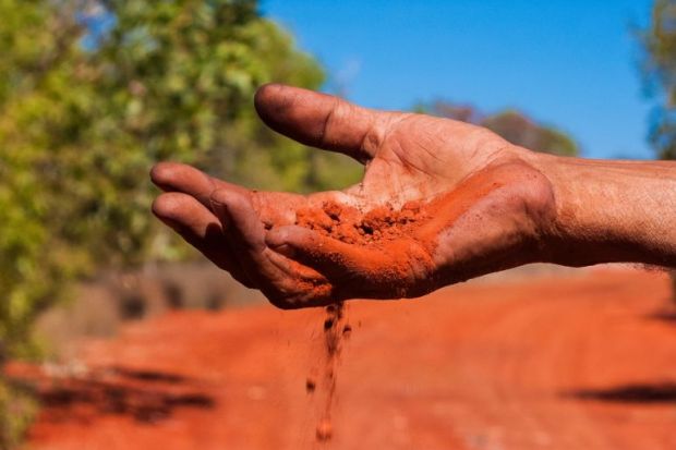 Red Australian earth slips through an Indigenous Australian’s fingers Red Australian earth slips through an Indigenous Australian’s fingers