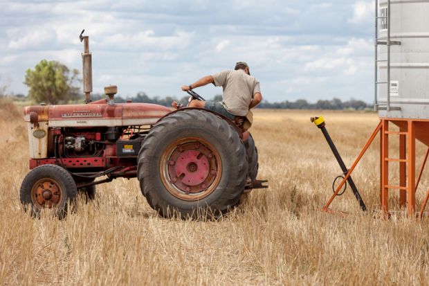 Moree, Australia - November 27, 2010: A farmer uses and old vintage tractor on a farm in Moree a major agricultural area in New South Wales, Australia.