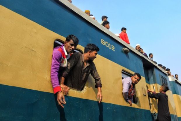 People lean out of a train window in Bangladesh, illustrating academic freedom
