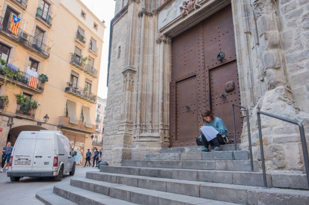 Barcelona, Spain, Oct. 12, 2017 A young woman student stops to study on the back steps of the Basilica Santa Maria Del Mar, a beautiful Gothic cathtedral in the El Born neighborhood.
