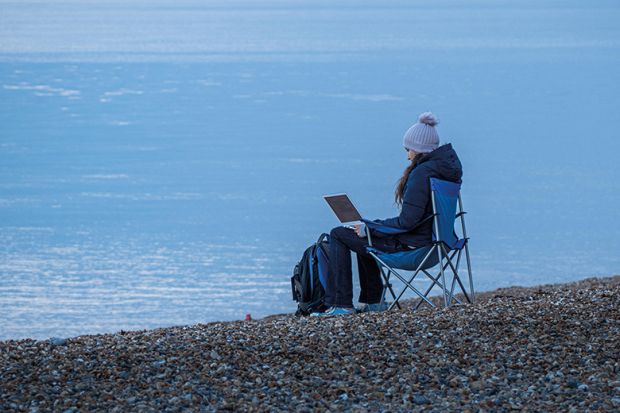 Working on laptop by sea in winter
