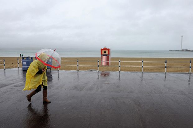 Person walking in the rain on beach in Weymouth
