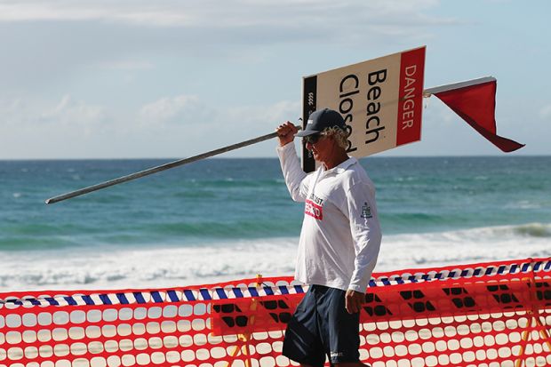 Lifeguard removing ‘beach closed’ sign illustrating open access publication
