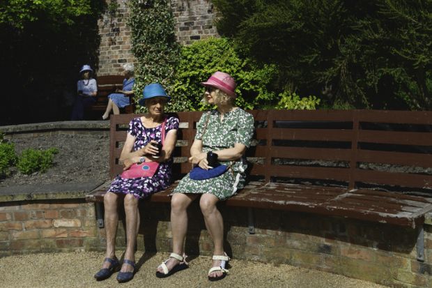 Beverley, UK - June 08, 2021 Two women dressed in colorful clothes and hats enjoy a fine spring morning in public gardens on June 08, 2021 in Beverley, Yorkshire, UK.