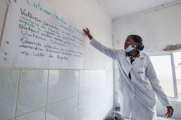 Bie, Angola - October 23, 2013 A midwife puts a poster in the wall of a public hospital about early detection and support to victims of gender based violence