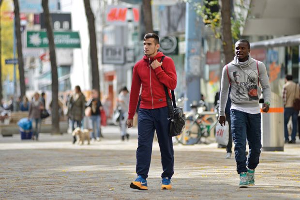 Black man and white man walking on high street