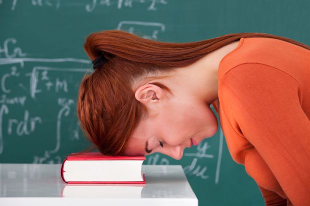 A bored academic leans her head on a book A bored academic leans her head on a book