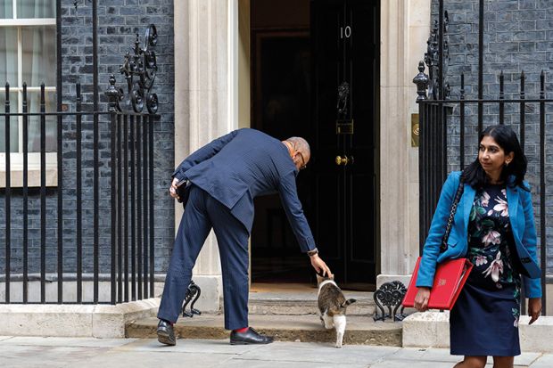Suella Braverman leaves Downing Street as James Cleverly, on his way in, strokes a cat