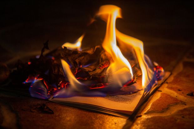 Burning paper, open book burns to ashes on concrete tiles