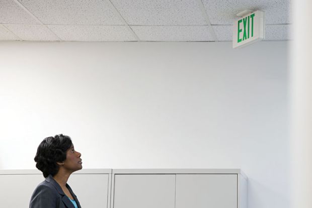 Businesswoman looking up at office 'Exit' sign