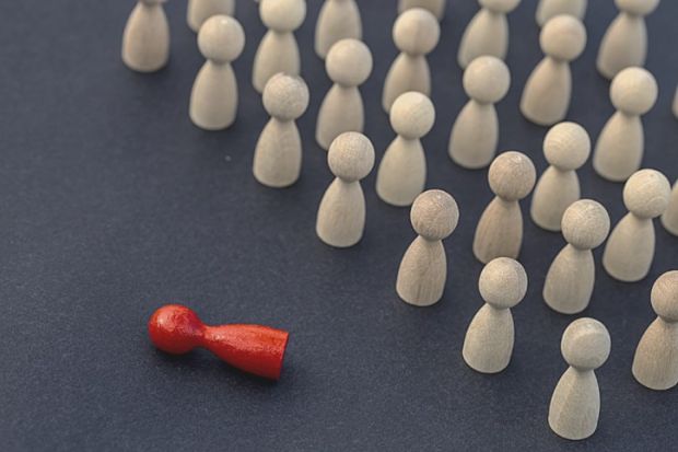 A red figurine lying on its side surrounded by brown ones, symbolising cancellation A red figurine lying on its side surrounded by brown ones, symbolising cancellation