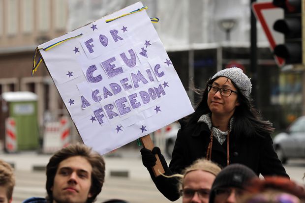 Woman holds a placard in support of academic freedom at CEU