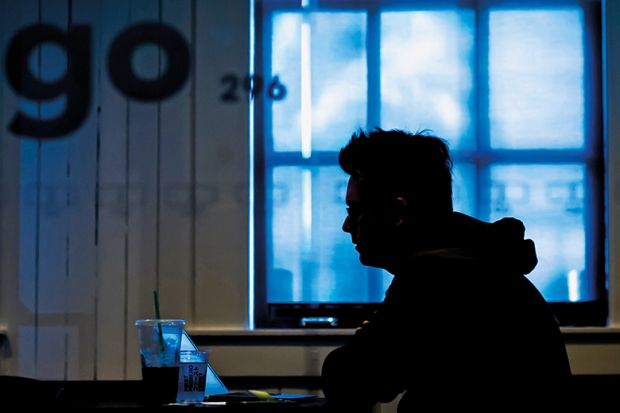 silhouette of anonymous student sitting at laptop