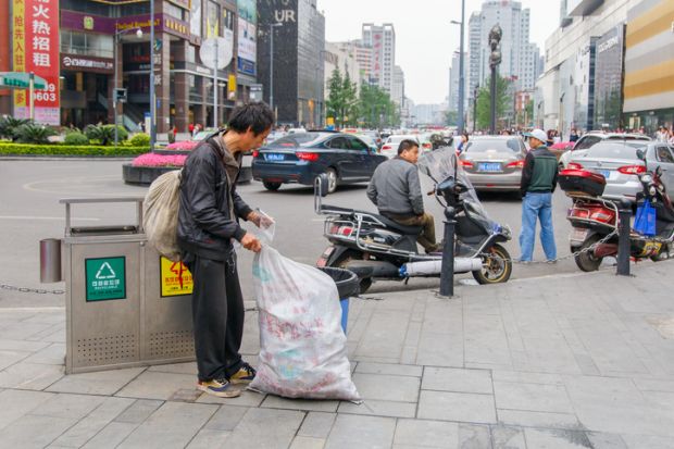 CHENGDU, CHINA - MAY 8, 2016 Chinese homeless looks for food and valuable in a garbage tin on May 8 2016 in Chengdu, China
