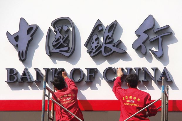 Two men work on a Bank of China sign