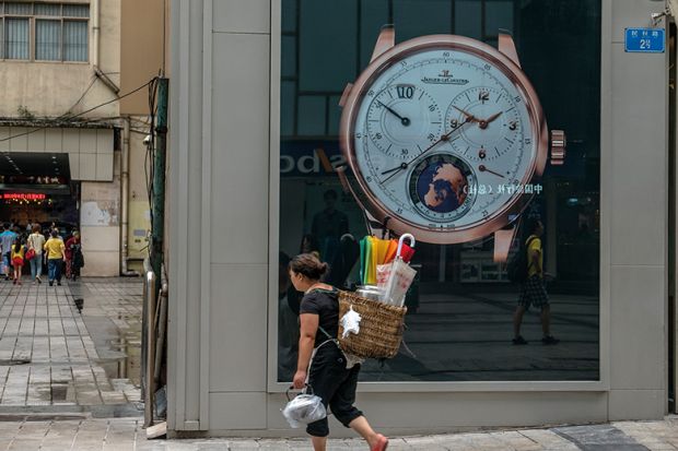 A local woman carries a bamboo basket, walking past a luxury watch shop at Jiefangbei CBD, Chongqing, 2015 
