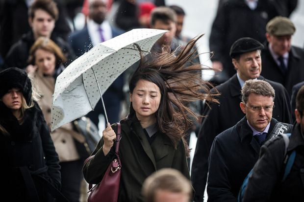 Asian woman holding umbrella on windy day