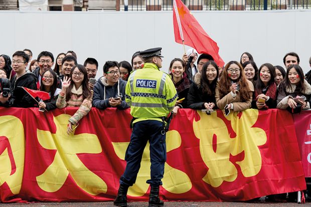 Chinese students show support for Chinese President Xi Jinping as he arrives to tour the National Graphene Institute at Manchester University in 2015