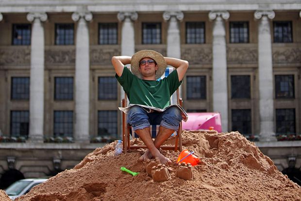 A person takes a break on a temporary city centre beach, Nottingham, UK. To illustrate a four-day week.