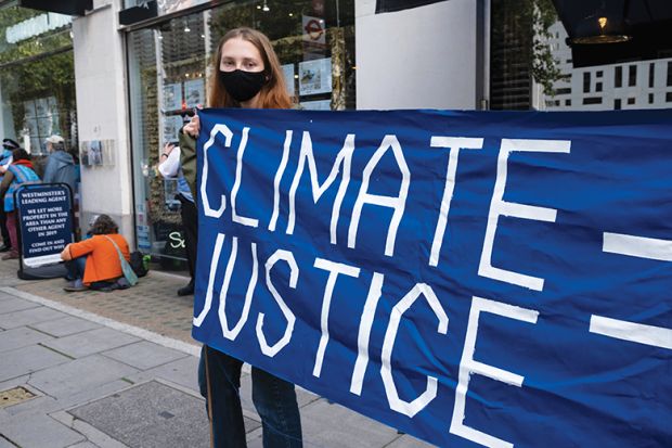 Woman holding climate justice protest banner Woman holding climate justice protest banner