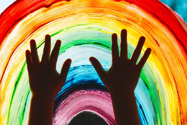 Close-up photo of child's hands touch painting rainbow on window