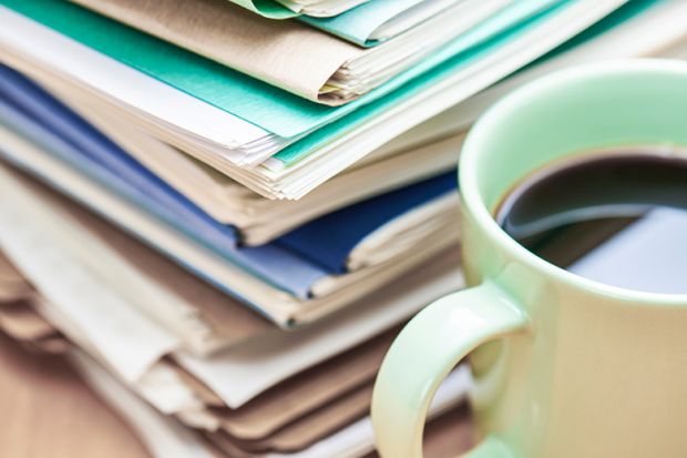 A stack of papers to mark and a cup of coffee
