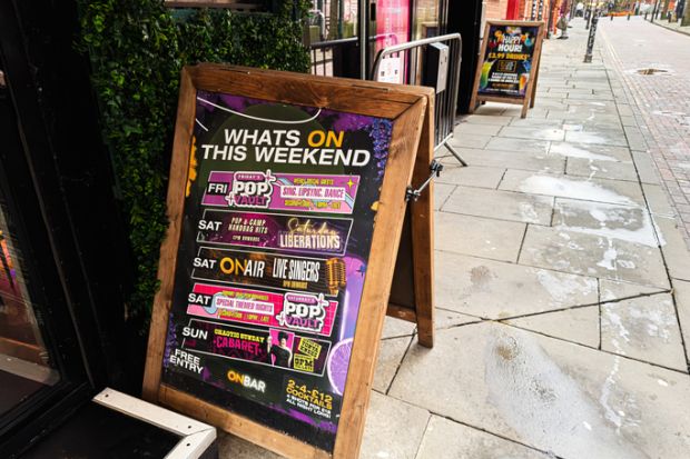 Colourful street sign outside a Manchester cafe promoting weekend events and drinks