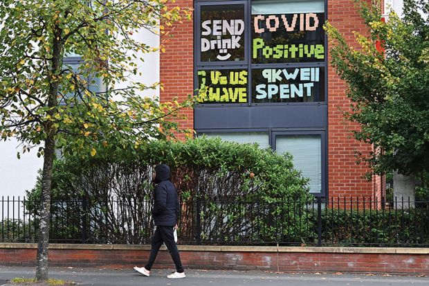 A man walks past messages pasted inside the windows of student accommodation at Manchester Metropolitan University