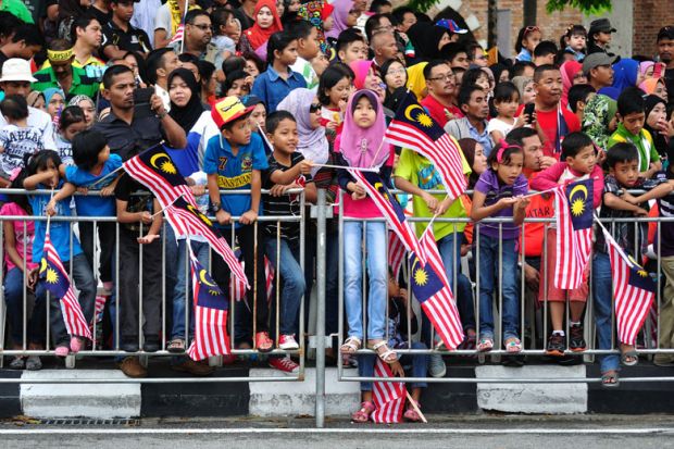 Crowd of people waving Malaysian flags