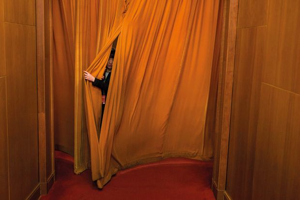 Person hiding behind curtain