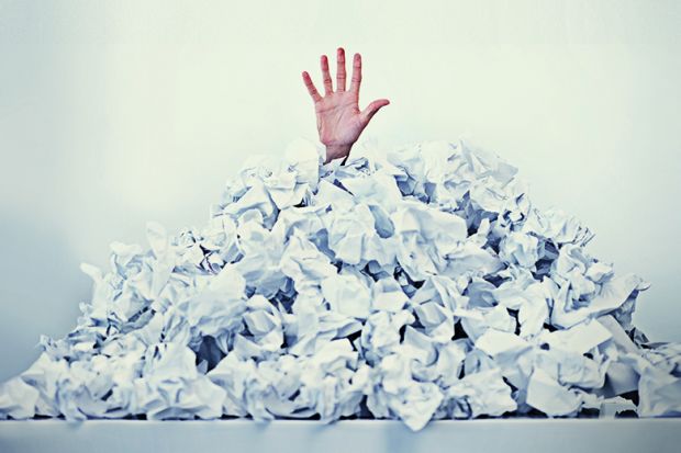 Hand sticking out of a mound of crumpled paper