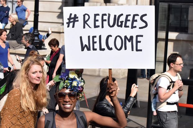 Demonstrator holding 'Refugees welcome' placard, London, England