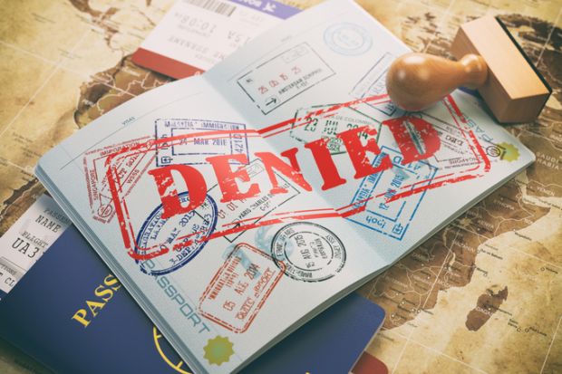 Passport with denied visa stamp on a map of the world 