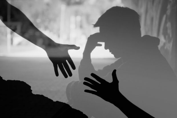 Hands reach for each other in front of a depressed man, symbolising suicide prevention