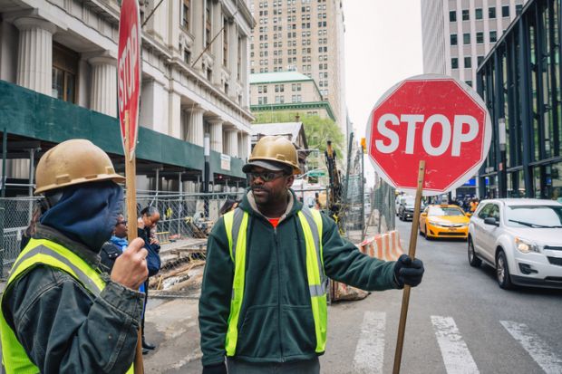A minority ethnic man with a sign to stop traffic A minority ethnic man with a sign to stop traffic
