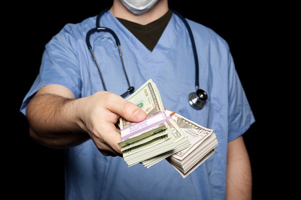 Male doctor holding out bank notes