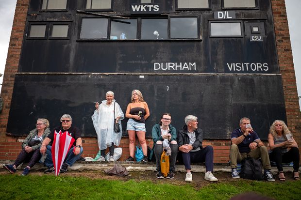 People sit next to a cricket scoreboard as they attend the Durham Miners Gala in Durham, England. To illustrate that elite universities face a ‘balancing act’ over local students.