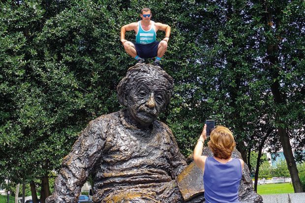 Man squatting on Albert Einstein memorial statue