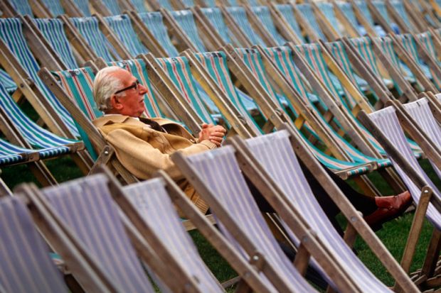 Elderly man sitting alone in rows of deckchairs
