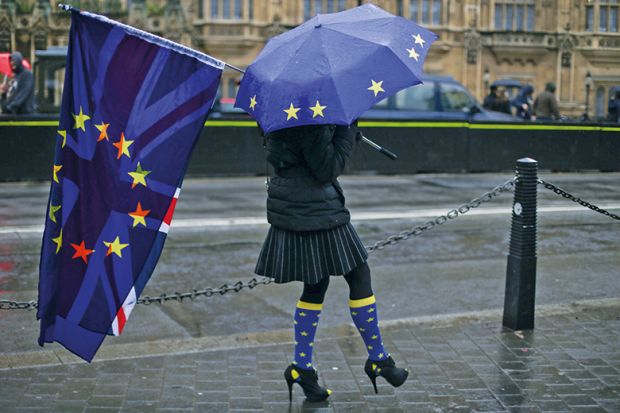 Person holds Union Jack and European Union flag and umbrella