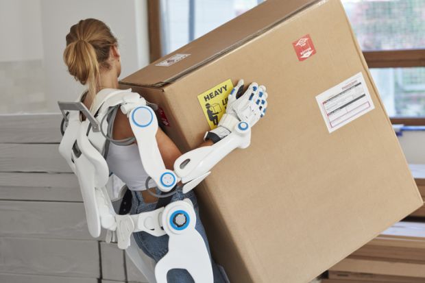 A woman lifts a heavy box with the help of a robotic exoskeleton, illustrating AI helping researchers