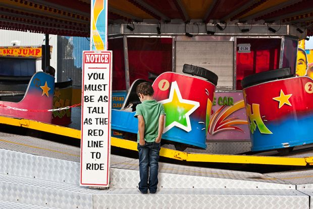 Fairground waltzers ride with minimum height safety notice and disappointed child. To illustrate minimum entry standards. Fairground waltzers ride with minimum height safety notice and disappointed child. To illustrate minimum entry standards.
