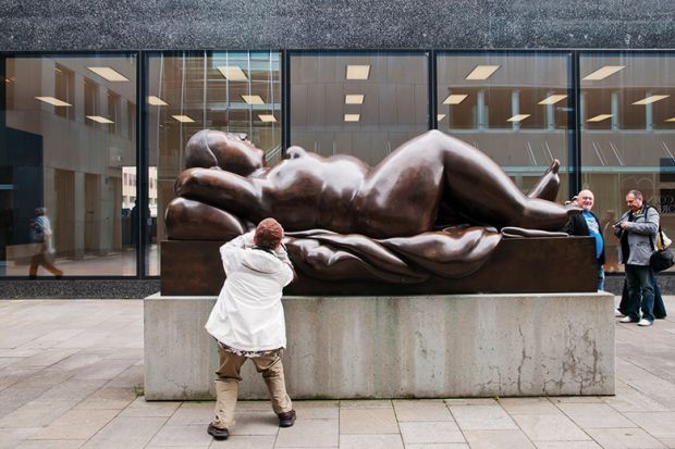 A tourist takes pictures of a sculpture of a voluptuous naked woman in Vaduz, Liechtenstein