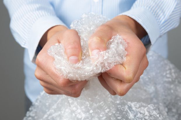 Female hands popping the bubbles of bubble wrap. Stress relief