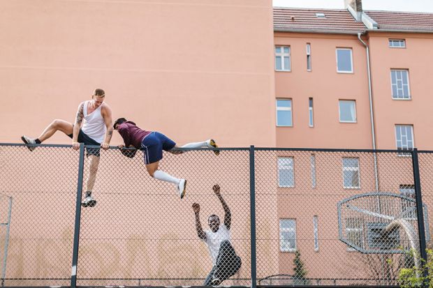 Men climbing over fence
