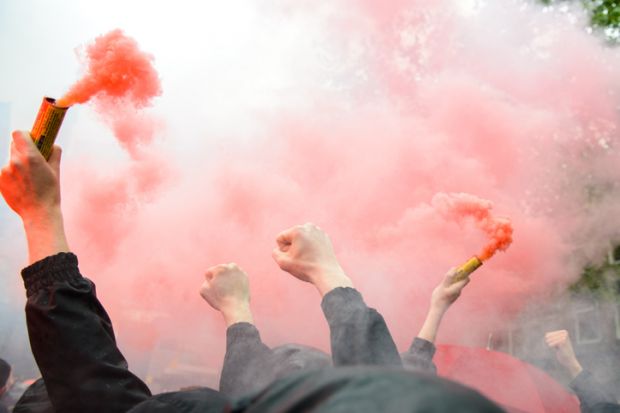 Dutch football fans clench fists and hold orange flares
